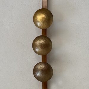 Lámpara Orion: tres esferas doradas martilladas en una tabla de madera.